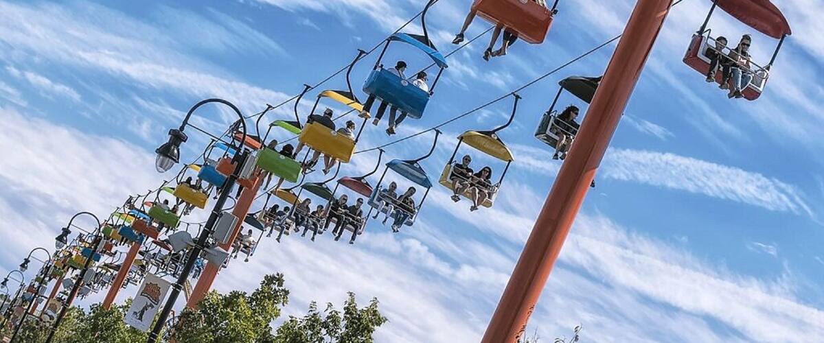A cable car system with multiple colorful gondolas against a blue sky with clouds.