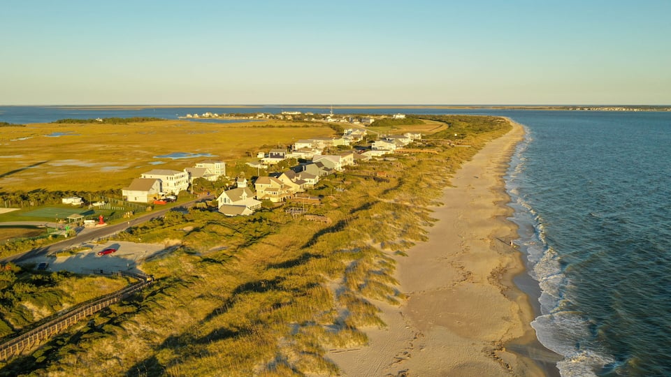 A coastal residential area with houses along the beach and a clear view of the ocean.