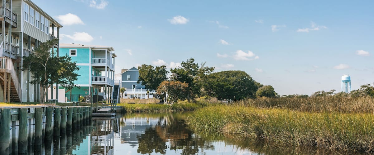 A calm waterway with buildings on one side and a water tower in the distance.