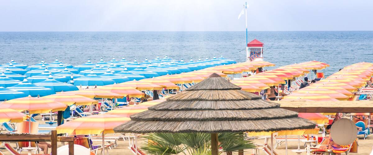 A beach with numerous umbrellas and sun loungers.