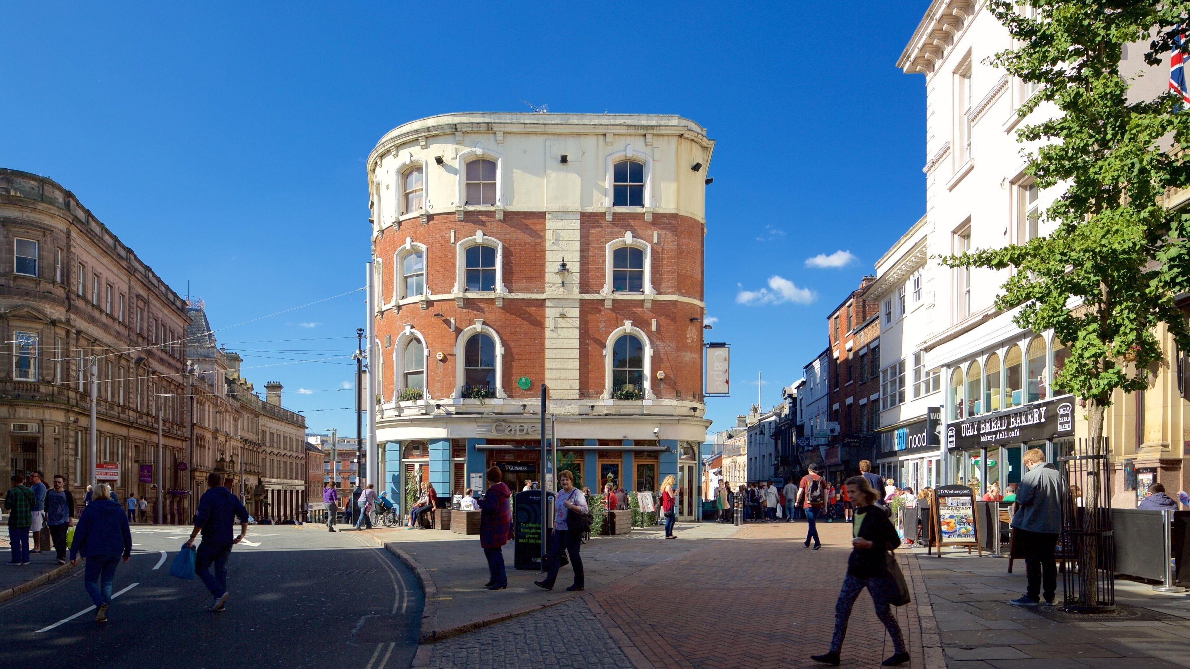 Una calle urbana concurrida, con edificios históricos, peatones y tiendas.