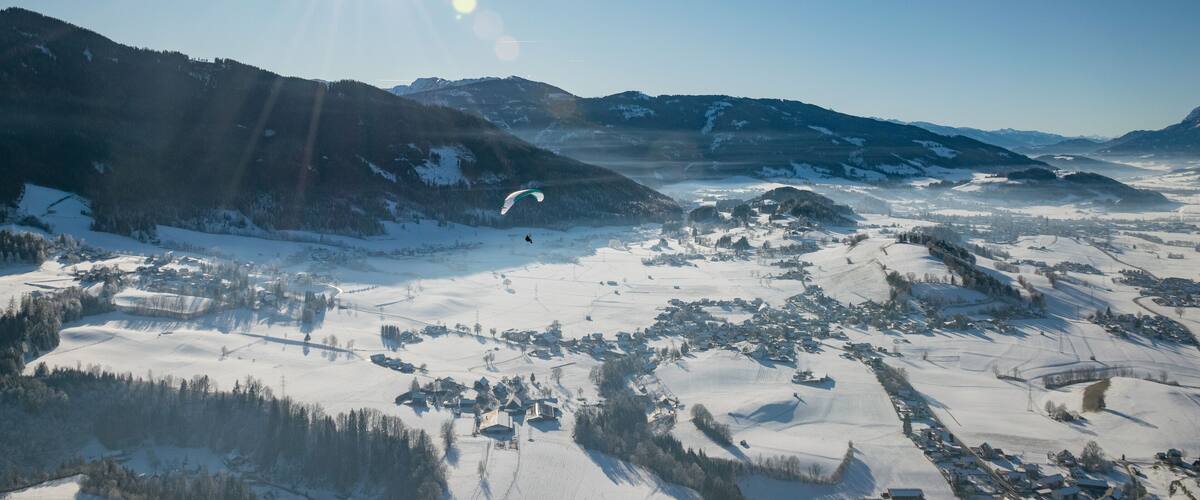 A snowy mountain landscape with a clear sky and a sun shining brightly.