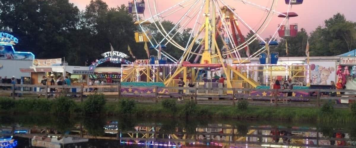 A Ferris wheel at dusk with its reflection in the water.
