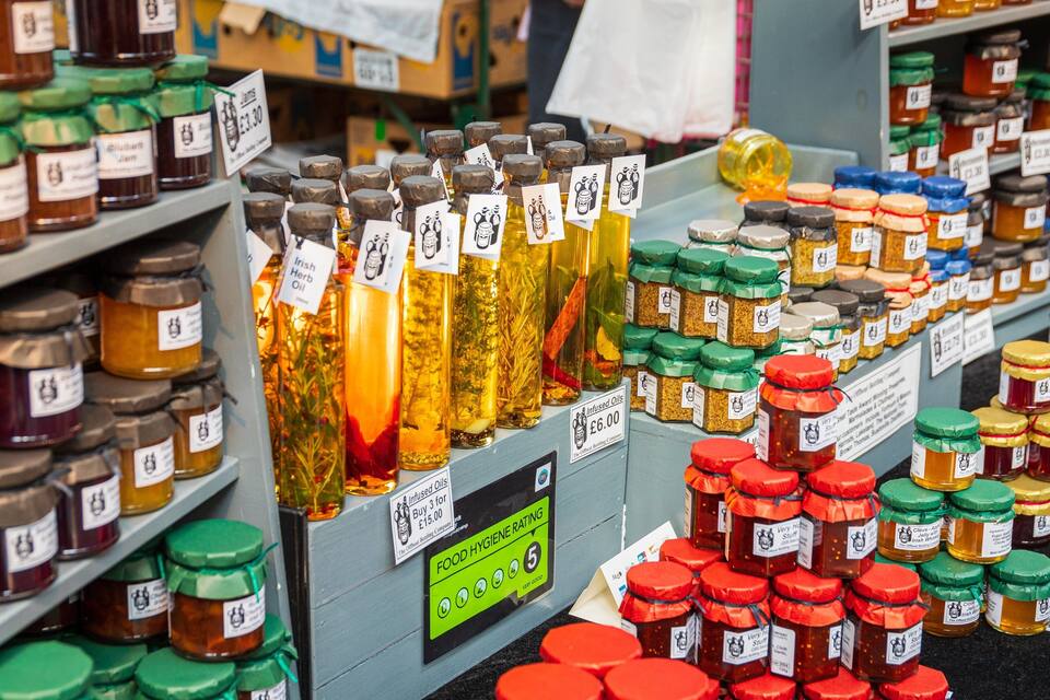 Estantes con varios frascos de miel y otros productos alimenticios con etiquetas de precio.