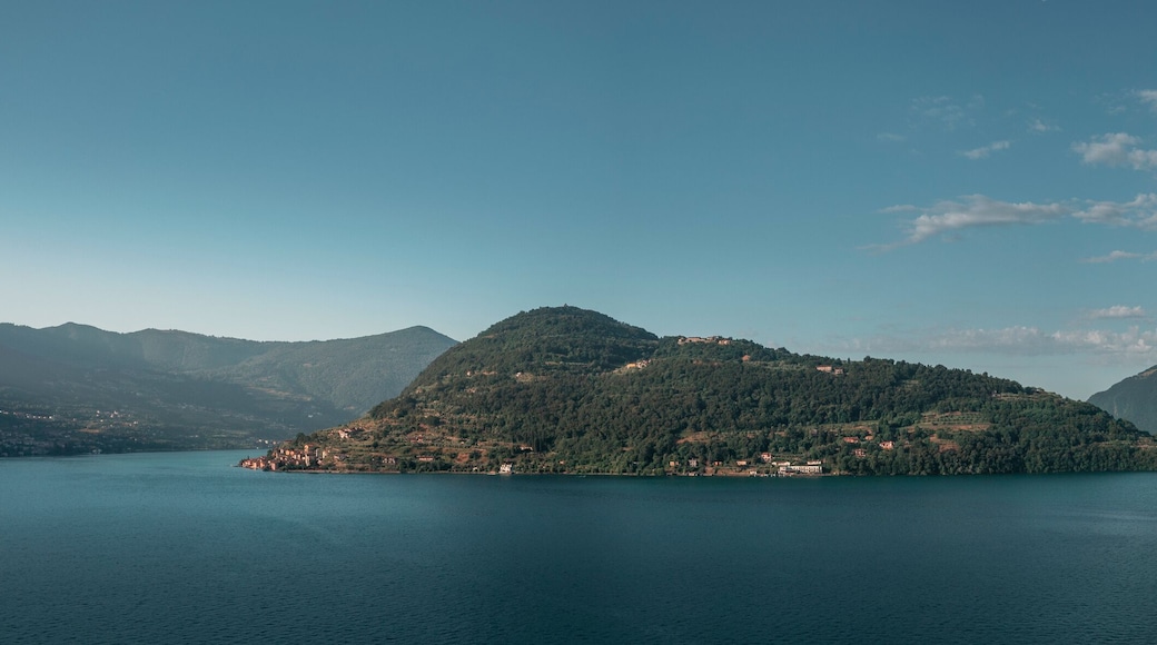 Mountain panorama at Lake Iseo with island Isola di Loreto and Monte Isola from above during afternoon, blue sky, Italy.