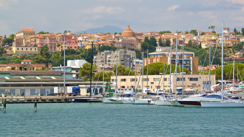 A marina with boats docked, a domed building, and a hillside of colorful buildings.