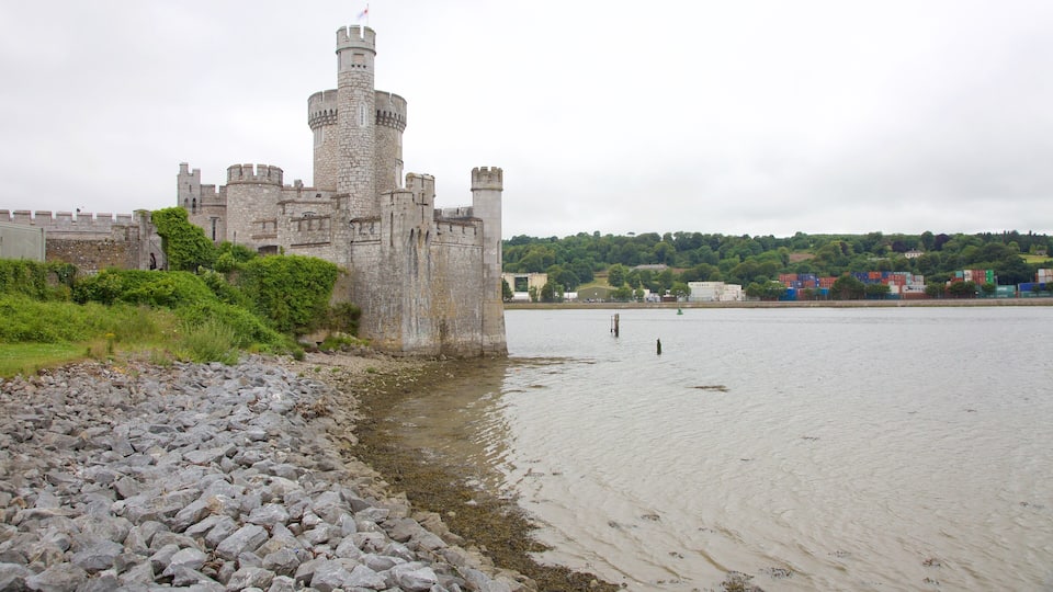 Um castelo histórico à beira de um rio com margem rochosa.