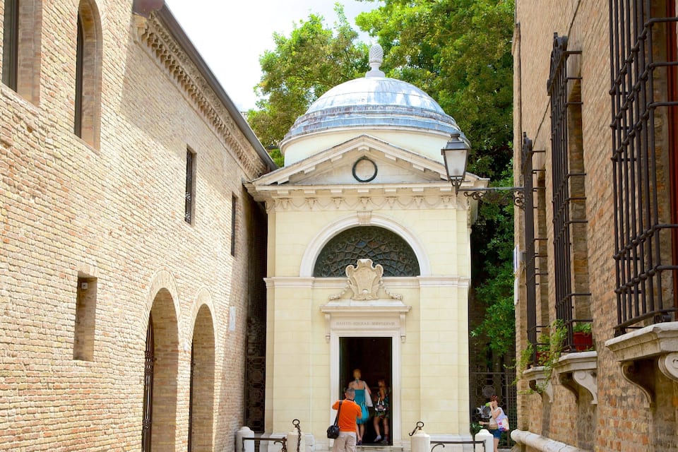 A narrow alleyway with a building featuring a dome and arched windows.