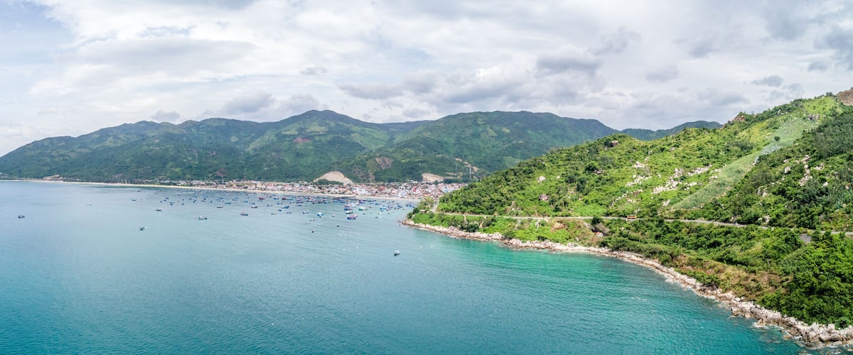 A coastal landscape with a bay, boats, and a town on the shore.