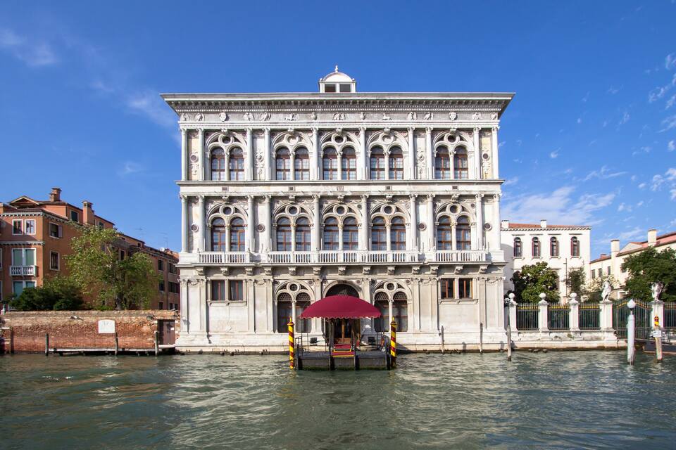 A historic building with ornate architecture and a canal in front.