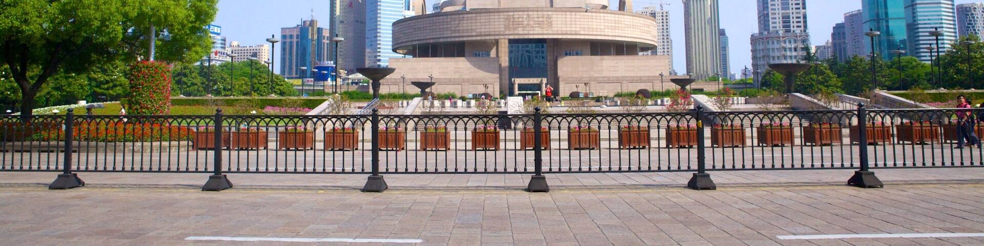 A cityscape with modern skyscrapers, a circular building with a dome, and a flagpole with a red flag.