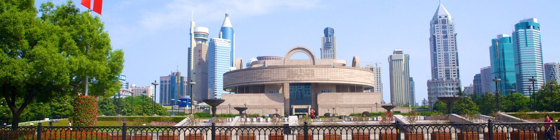 A cityscape with modern skyscrapers, a circular building with a dome, and a flagpole with a red flag.