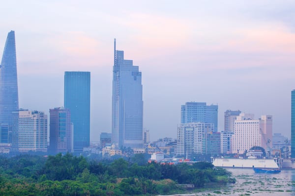A city skyline with modern skyscrapers and a river with boats.