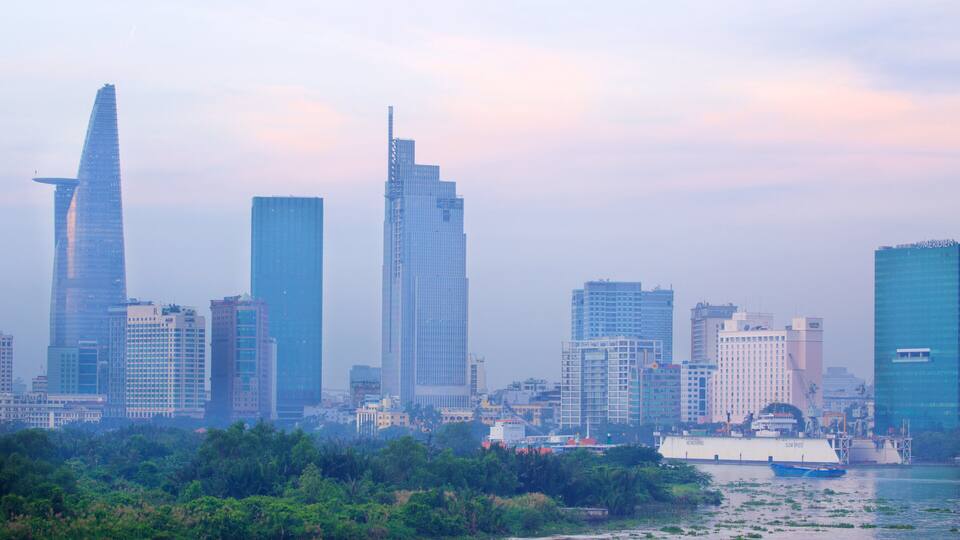 A city skyline with modern skyscrapers and a river with boats.
