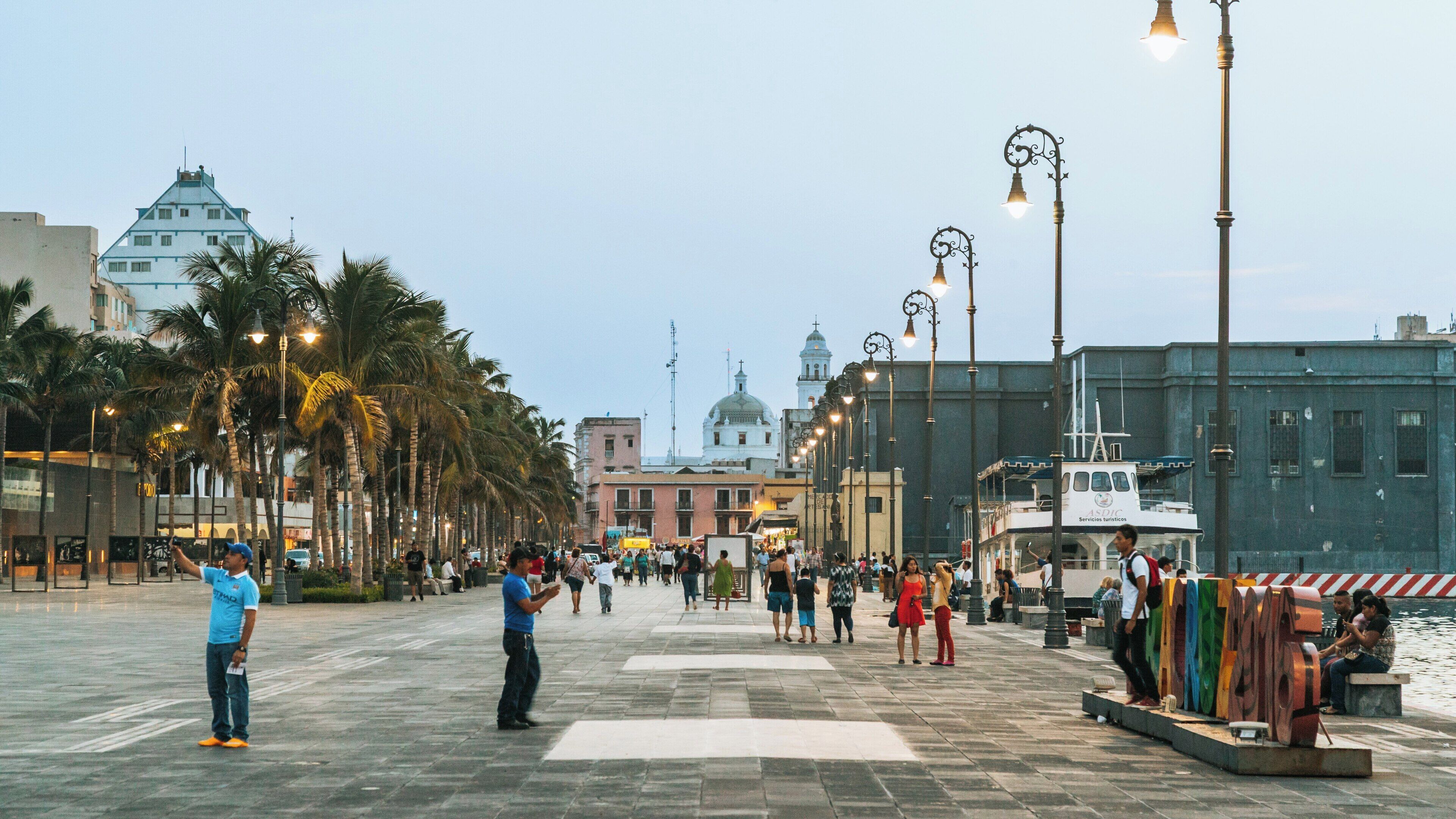 Visitors explore Veracruz Harbour in Veracruz, Mexico during an evening stroll amidst lively palm trees and vibrant local culture