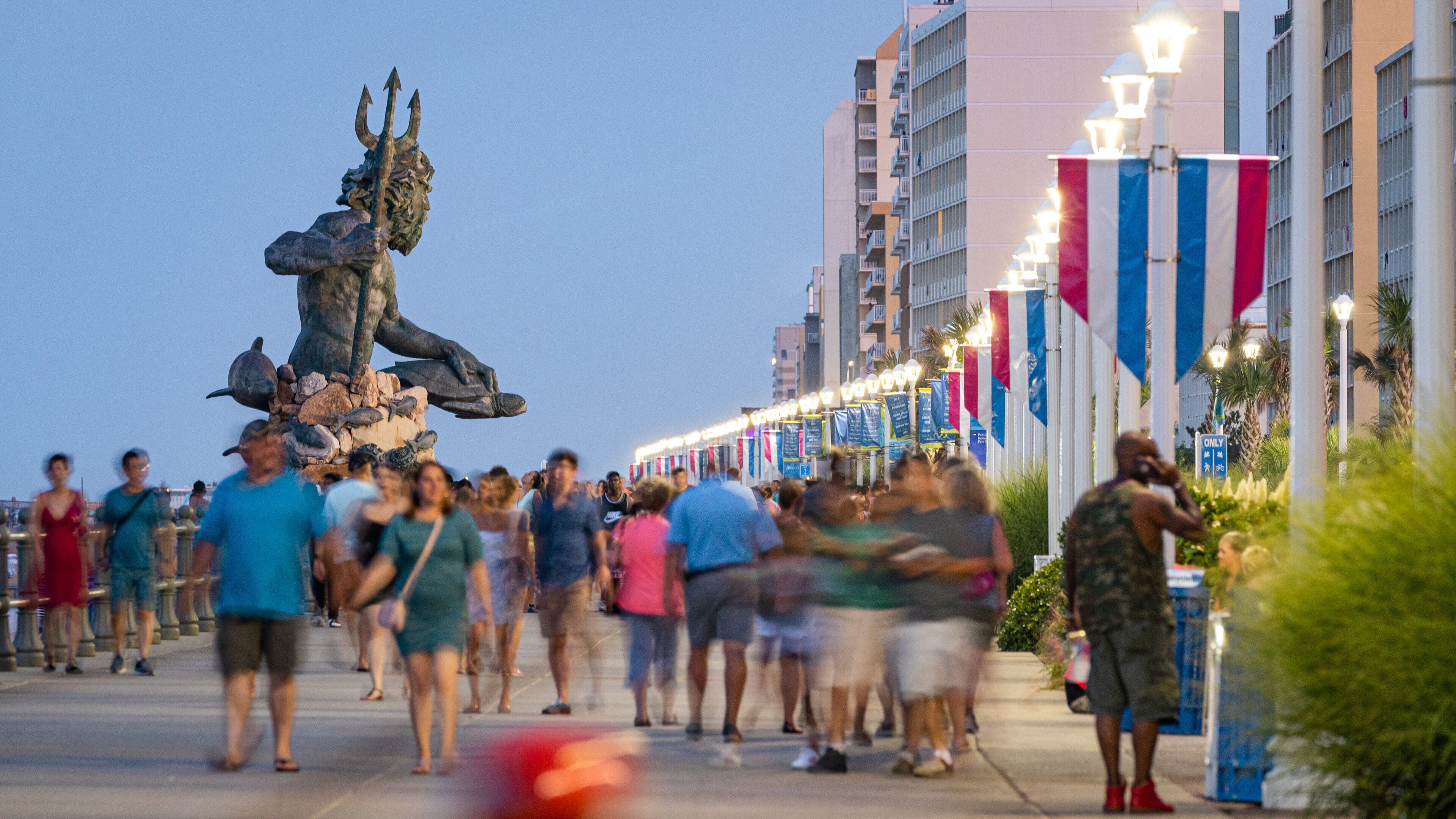 A busy pedestrian area with a statue of a figure holding a trident, surrounded by people.