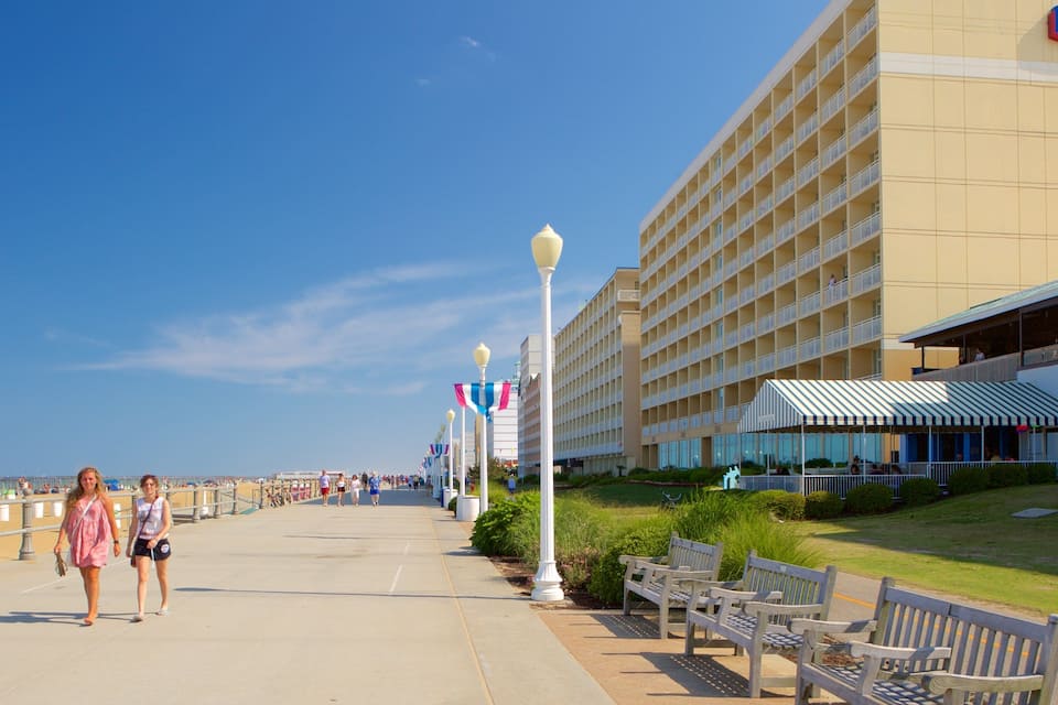 Um calçadão com bancos, um hotel e um céu azul límpido.