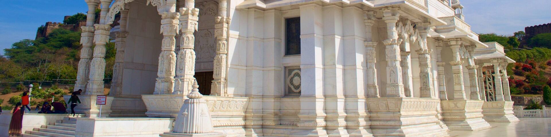 A white temple with intricate carvings and a large dome.