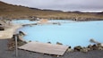 A geothermal spa with multiple pools surrounded by rocky terrain and mountains in the background.