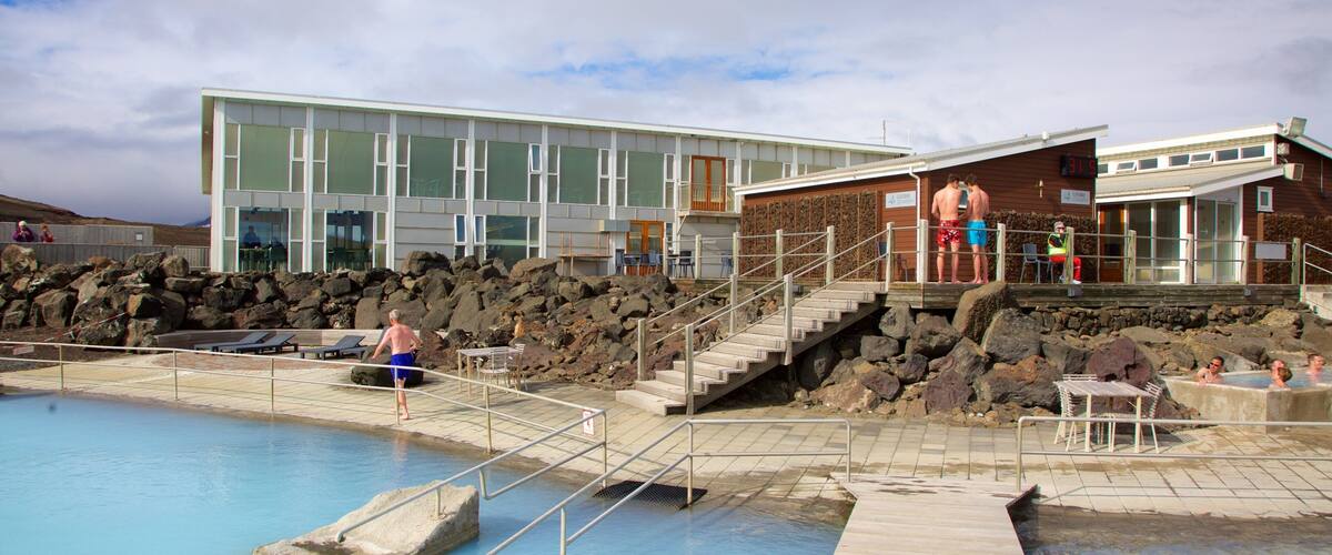 A geothermal spa with a pool, wooden deck, and a modern building with large windows.