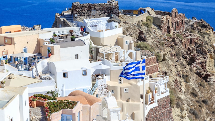 Castillo area with castle and byzantine ruins and greek flag in Oia village, Santorini island, Greece