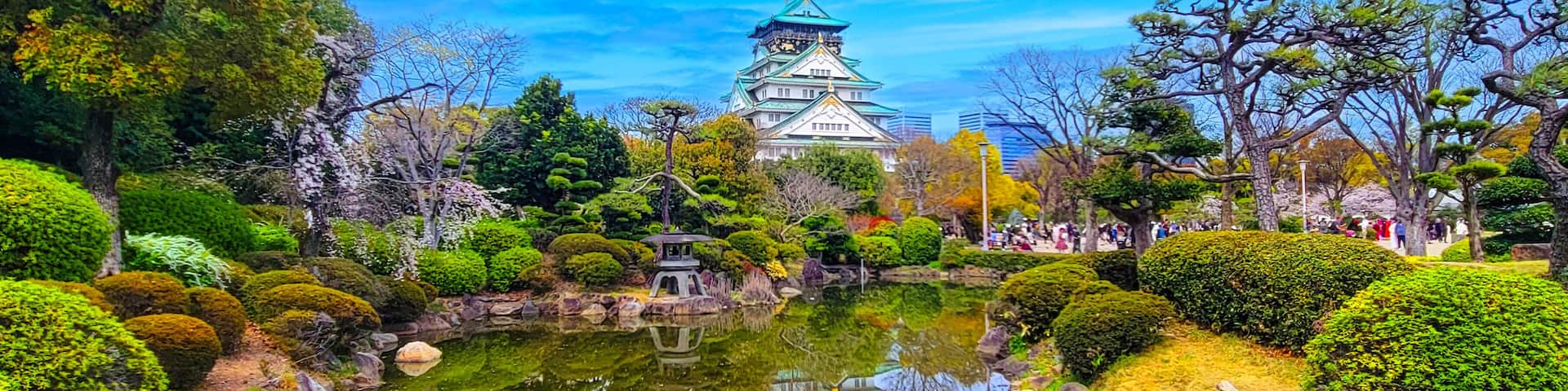 A traditional Japanese castle with a pond and well-manicured gardens.
