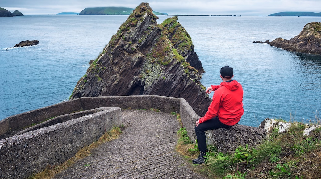 Tourist watching giant cliffs and irish islands at the Dunquin Pier, Dingle Peninsula, Ireland