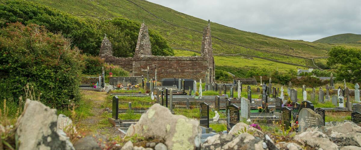 A cemetery with stone crosses and a ruined stone building.