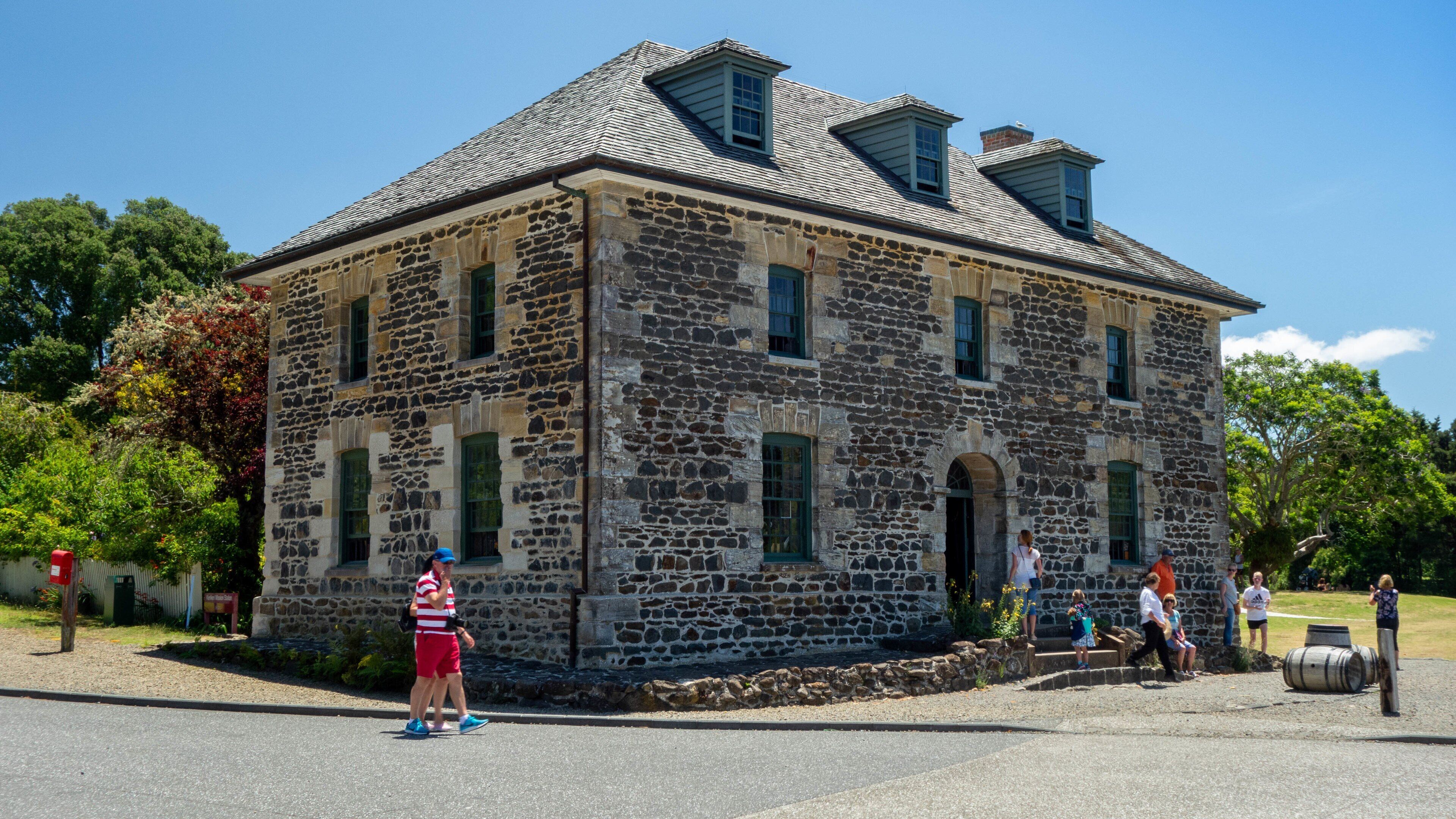 A historic stone building with a steep roof and multiple windows.
