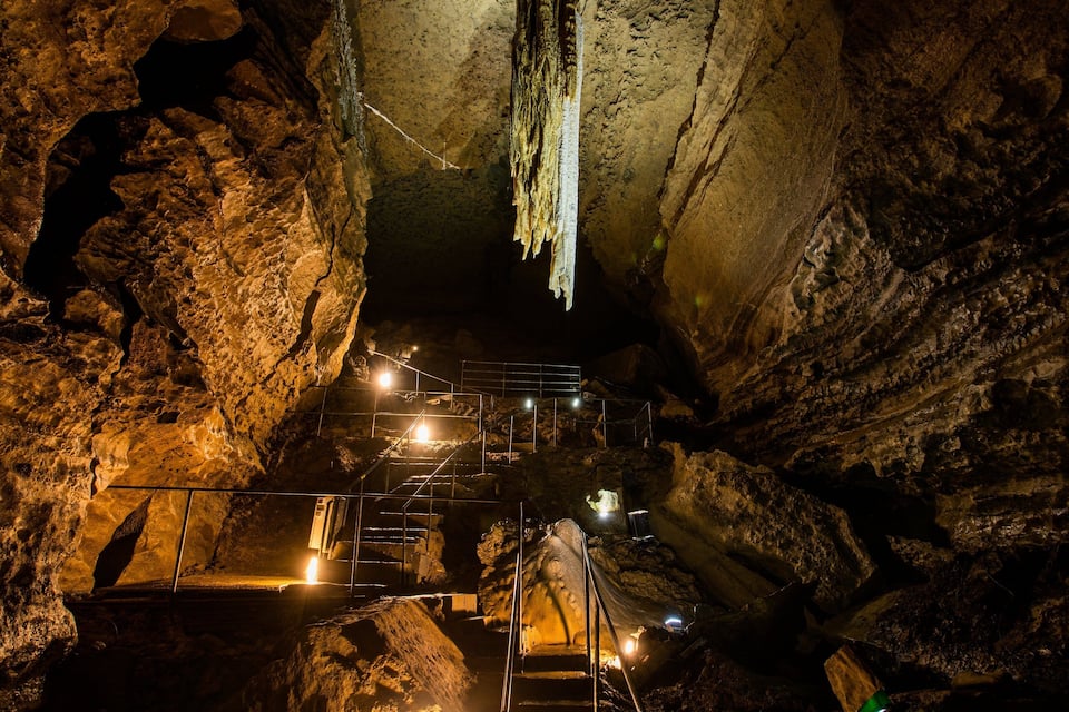 A cave with illuminated staircases and stalactites.