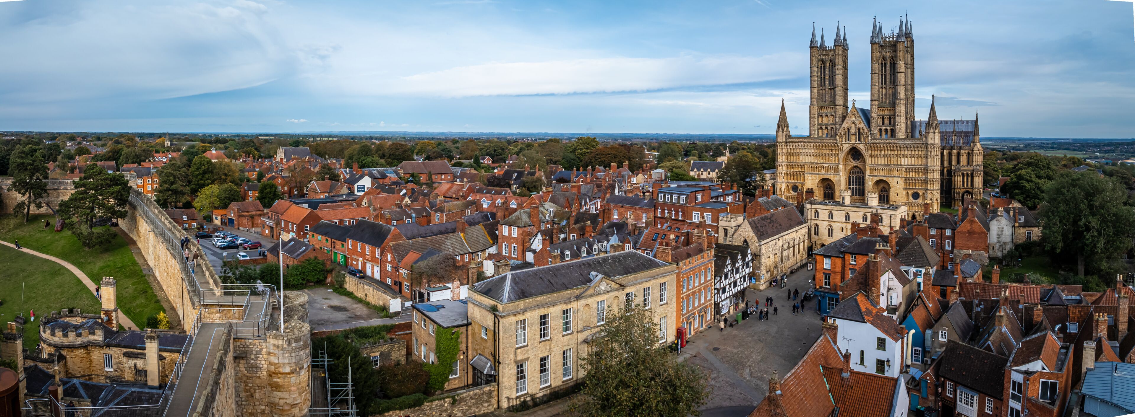 A historic cathedral with twin spires, surrounded by traditional red-brick buildings and a stone fortification.