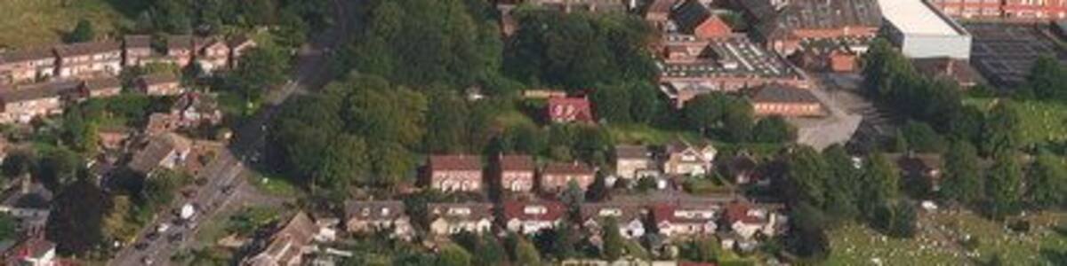 Eine Vogelperspektive auf eine ländliche Gegend mit einem großen Fußballfeld, umliegenden Häusern und einem kleinen Dorf.