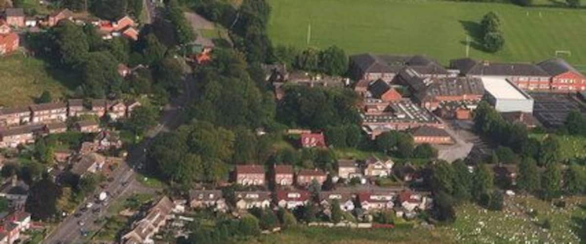 Vista aérea de una zona rural con un gran campo de fútbol, casas aledañas y un pequeño pueblo.