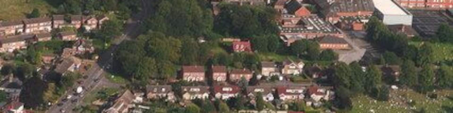 An aerial view of a rural area with a large football field, surrounding houses, and a small village.