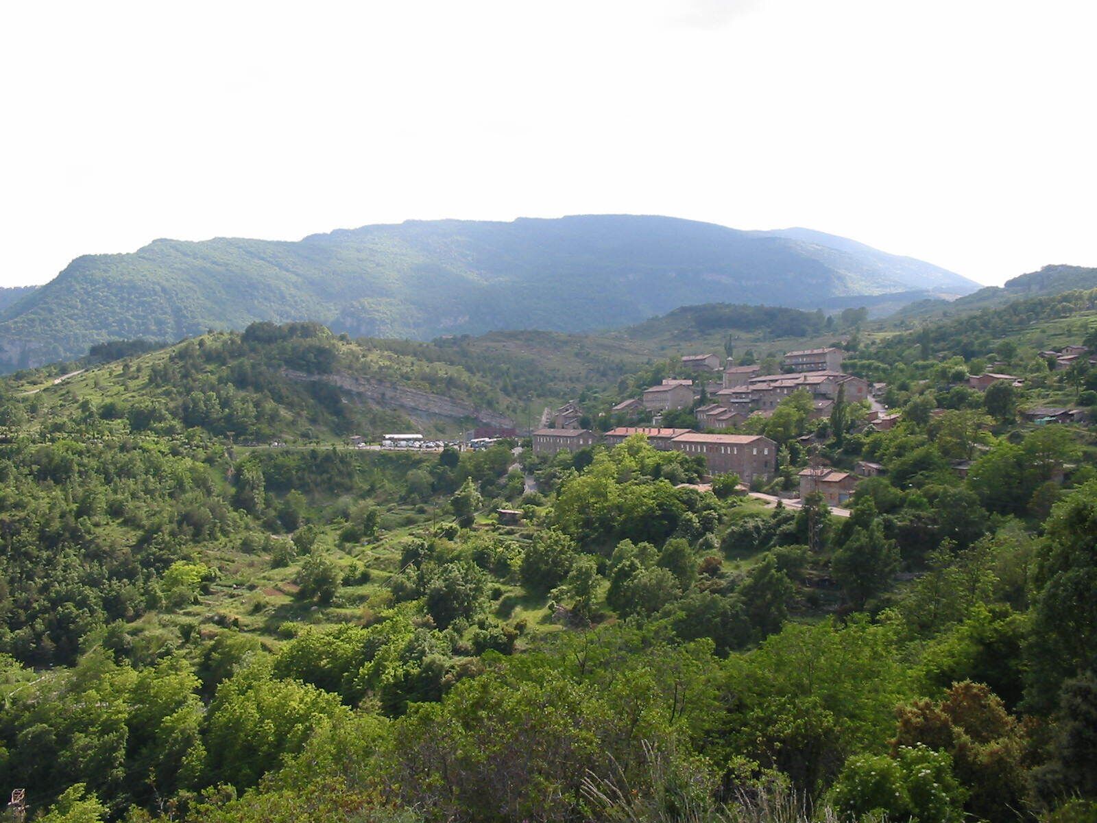 A village nestled in a valley surrounded by lush green hills and mountains.