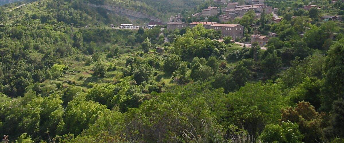 A village nestled in a valley surrounded by lush green hills and mountains.