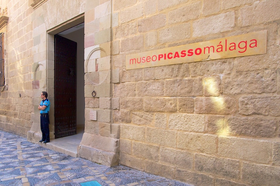 Kivinen rakennus, jonka yläpuolella on kyltti, jossa lukee ”museoPICASSOMÁLAGA”, ja sen edessä seisoo henkilö.