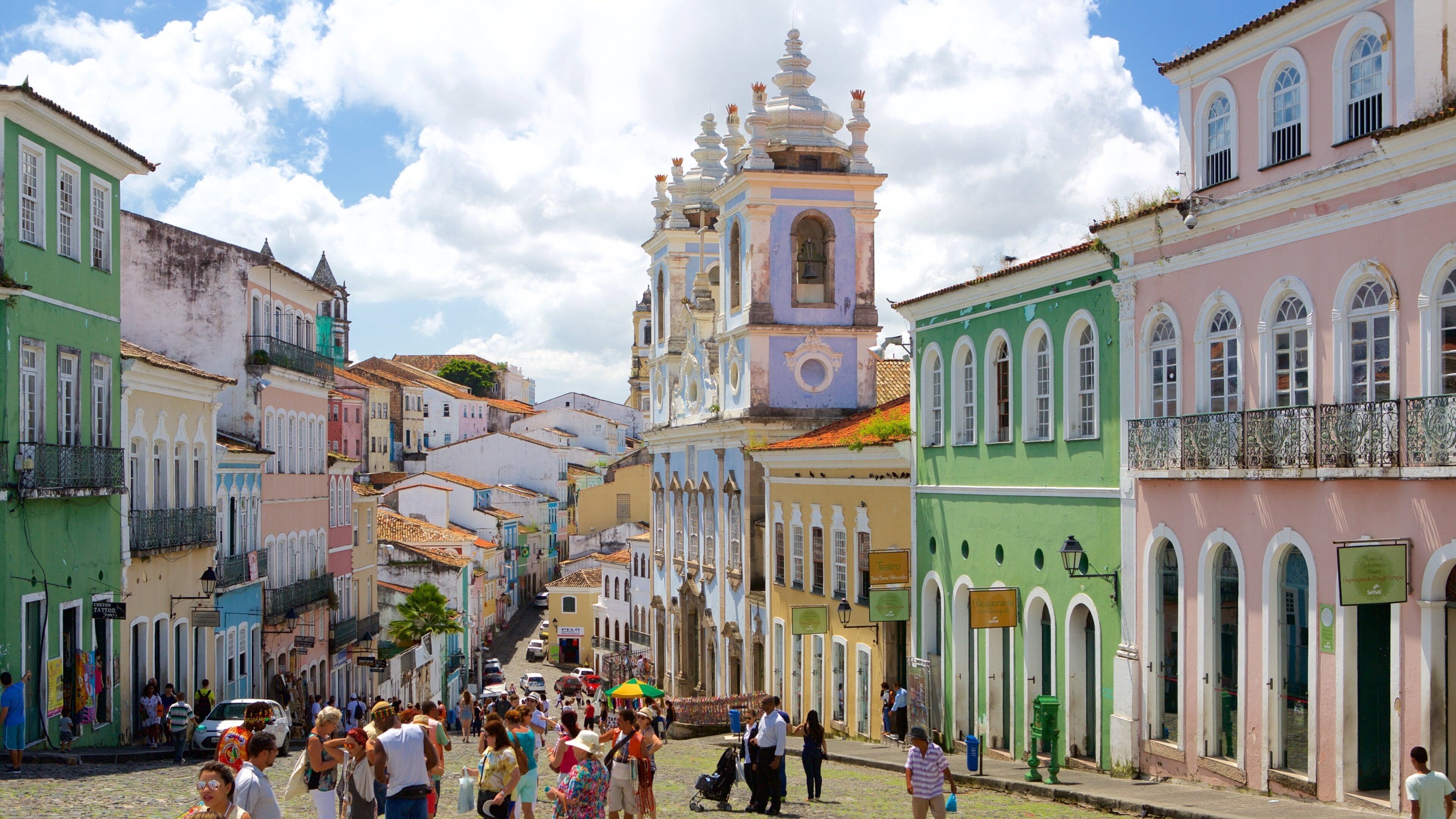 A bustling street with colorful buildings and a prominent church with a bell tower.