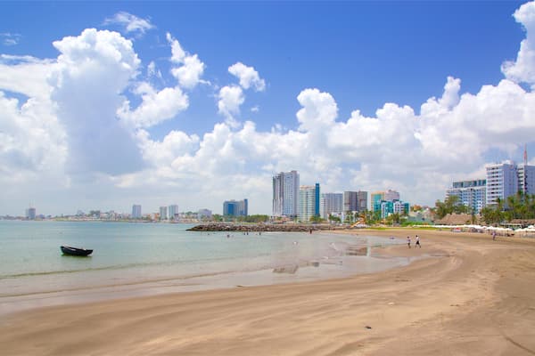 A beach with a boat, sandy shore, and a city skyline in the background.