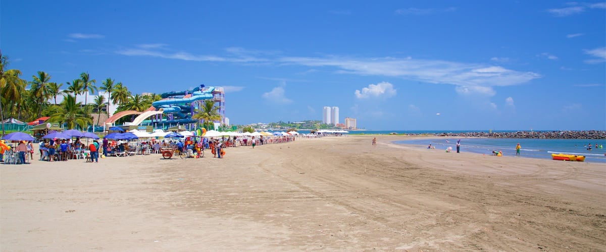 A beach with a water park, palm trees, and a clear blue sky.