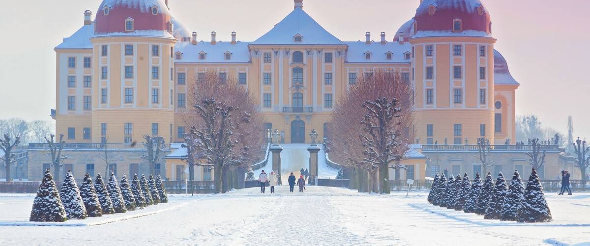 A large building with two domes and a snow-covered pathway leading to it.