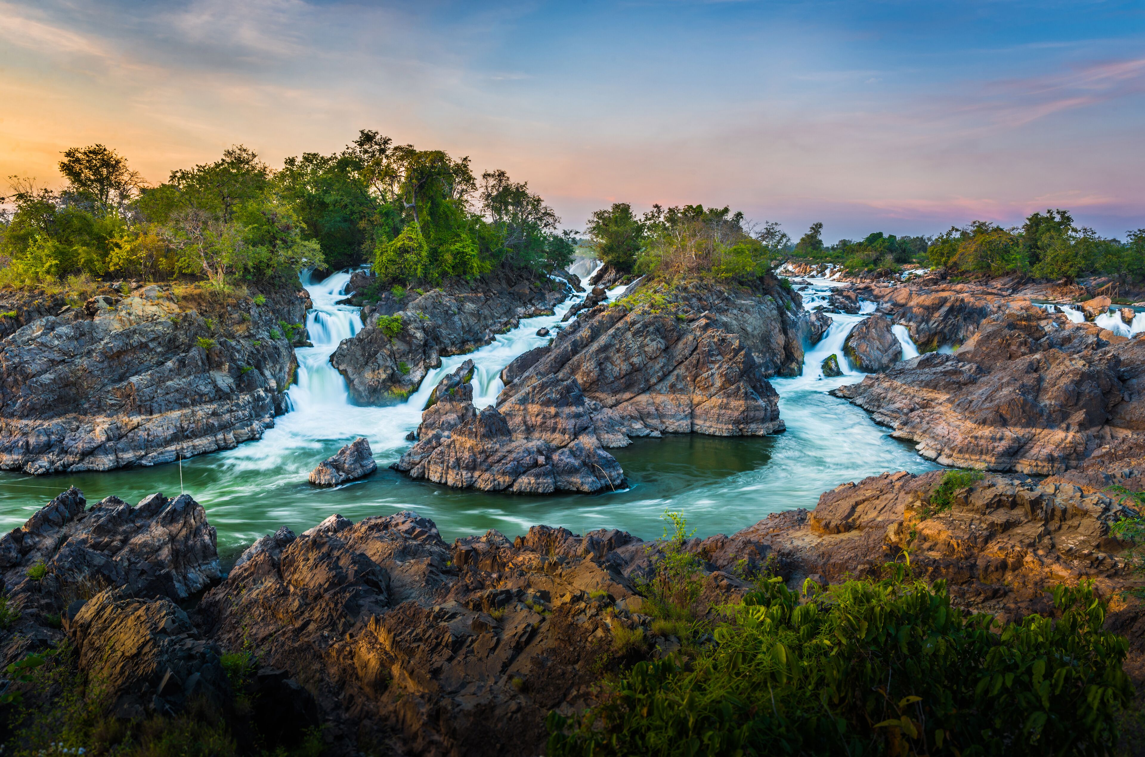 A waterfall cascading over rocky terrain surrounded by lush greenery.