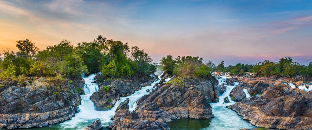 A waterfall cascading over rocky terrain surrounded by lush greenery.