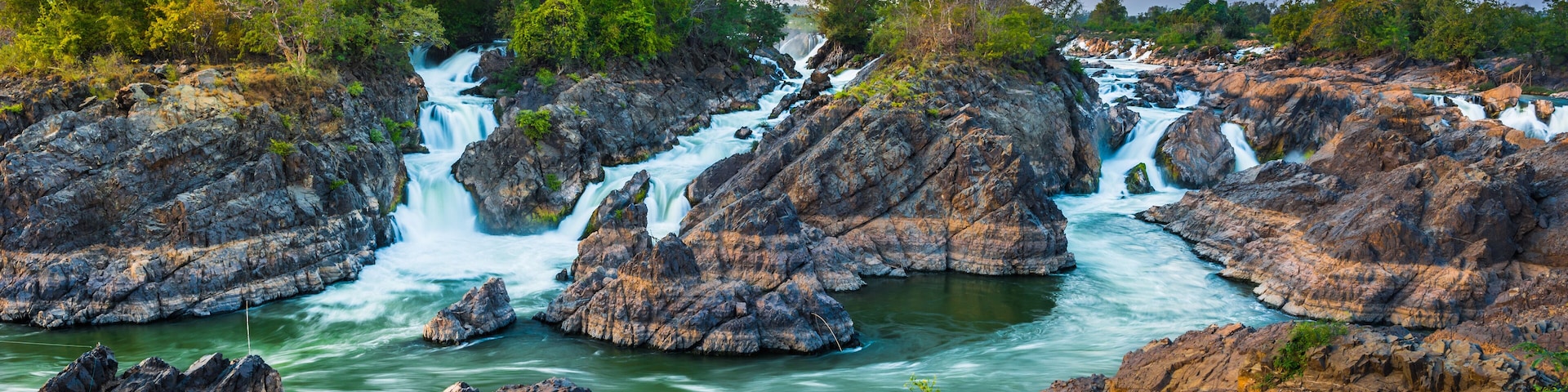 A waterfall cascading over rocky terrain surrounded by lush greenery.