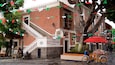 Un edificio con una escalera y un letrero que dice "GALERIA". Hay banderas coloridas colgadas en la parte superior del edificio.