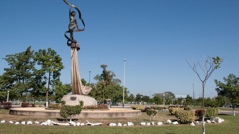 Uma estátua em um parque com árvores e céu claro.