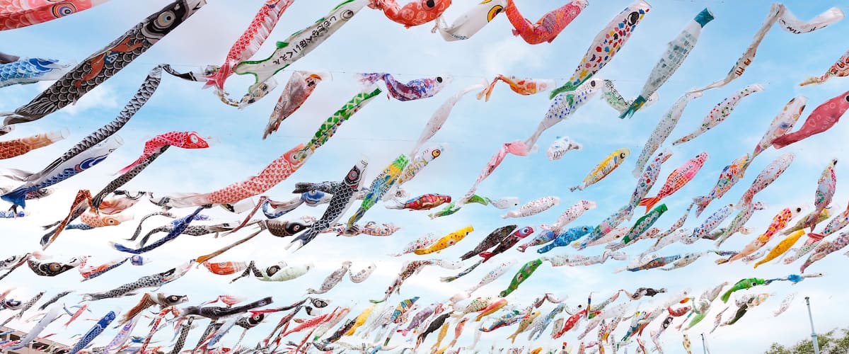 A large crowd gathered under numerous colorful kites.