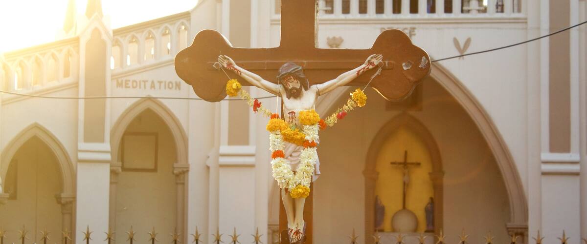 A crucifixion scene with a cross and a figure of Jesus, set against a church with a 'MEDITATION' sign.