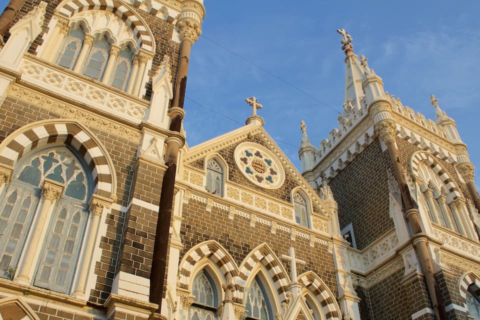 A Gothic-style church with intricate brickwork, pointed arches, and a prominent clock tower.