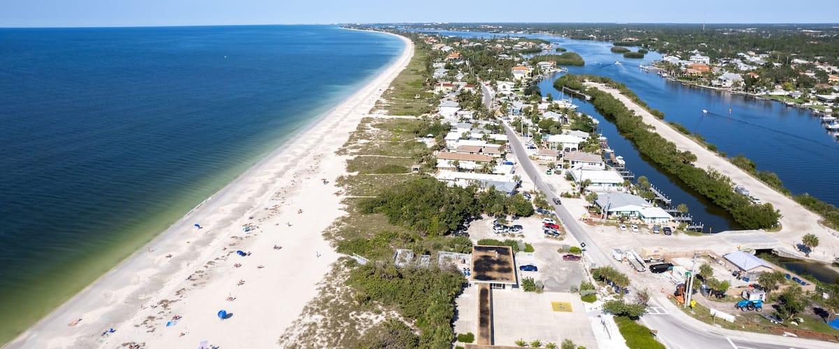 A coastal town with a beach, marina, and clear blue waters.